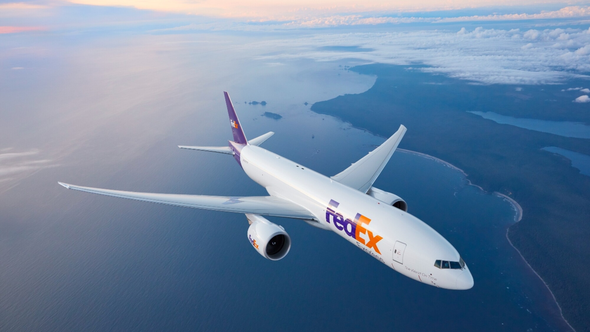Avión de carga de FedEx Express sobrevolando la costa al atardecer