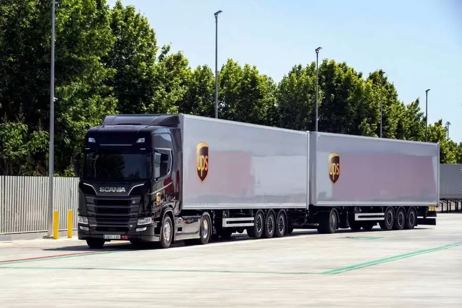 Camión de UPS con dos remolques aparcado en una plataforma logística